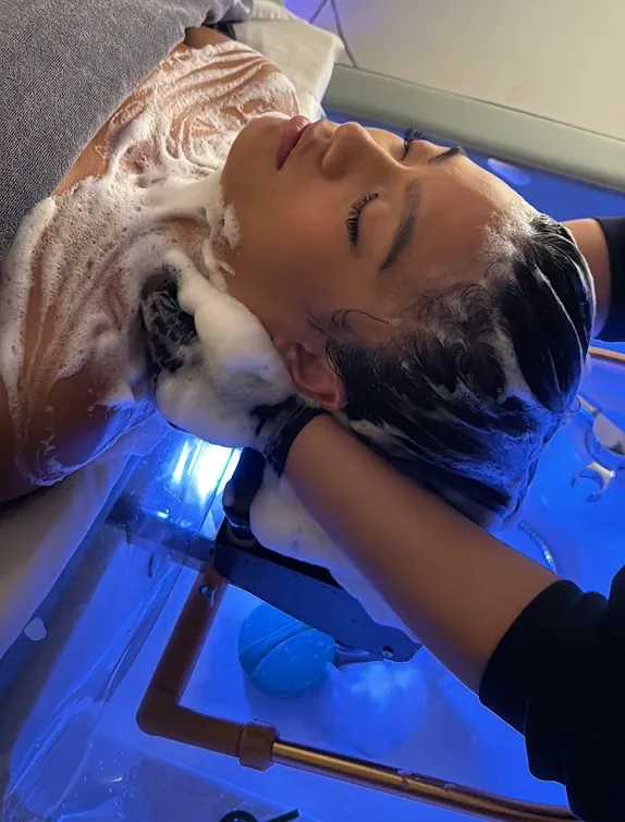 Purifying shampoo lather worked through the scalp during the cleansing stage of a scalp treatment at Soul Massage